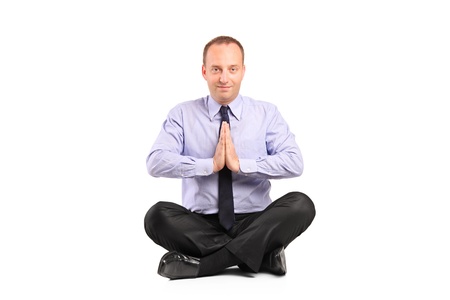 A businessman doing yoga exercise seated on a floor isolated on white background の写真素材
