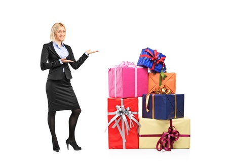 Full length portrait of a female in suit gesturing and pile of gifts isolated on white backgroundの写真素材