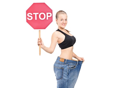 A weightloss girl holding a traffic sign stop isolated on white backgroundの写真素材