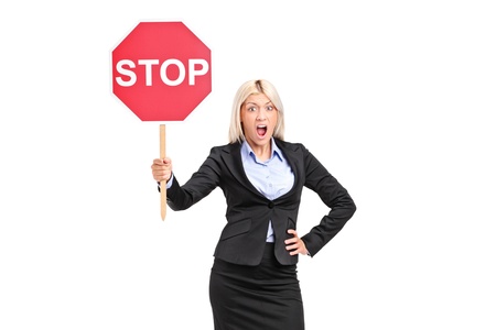 Young businesswoman holding a traffic sign stop isolated on white backgroundの写真素材