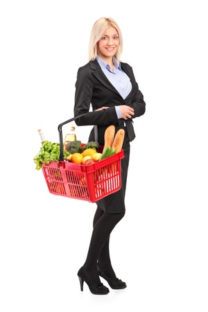 Full length portrait of a young woman holding a shopping basket full with groceries isolated on white backgroundの写真素材