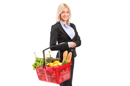 A young woman holding a shopping basket with groceries isolated on white backgroundの写真素材