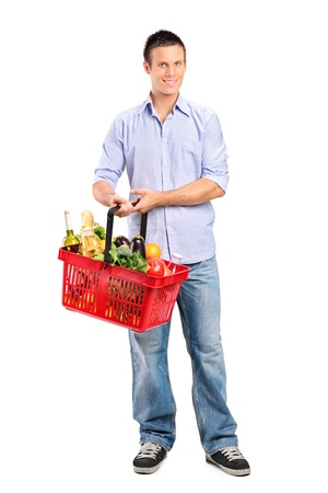Full length portrait of a young male holding a full shopping basket isolated on white backgroundの写真素材