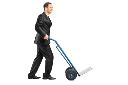 Smiling businessman pushing an empty handtruck isolated on white backgroundの写真素材