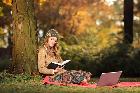 Young woman reading a book in the parkの写真素材