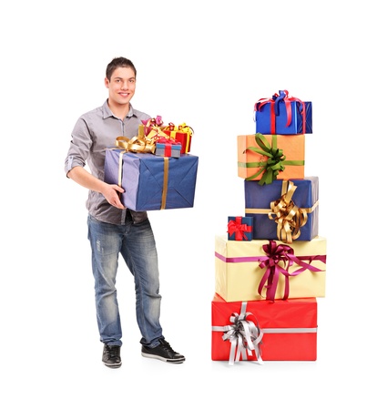 Full length portrait of a boy holding a gift next to a pile of gifts isolated against white backgroundの写真素材