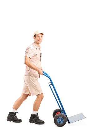Full length portrait of a manual worker pushing an empty handtruck isolated on white backgroundの写真素材