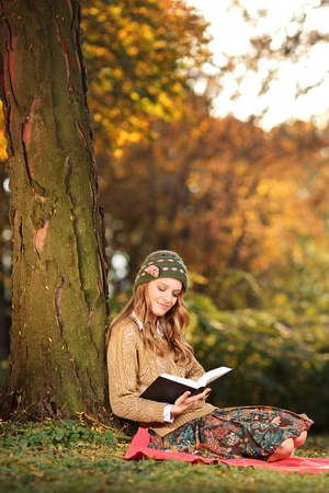 Smiling young woman reading a book in the parkの写真素材
