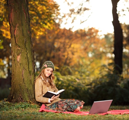 A young woman reading a book in the city parkの写真素材