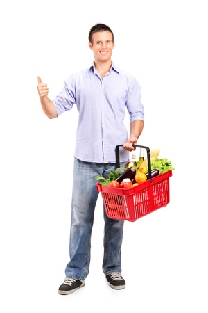 Full length portrait of a smiling man holding a shopping basket and giving thumb up isolated on white backgroundの写真素材