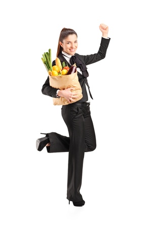 Full length portrait of a young female holding a paper bag with groceries isolated on white backgroundの写真素材