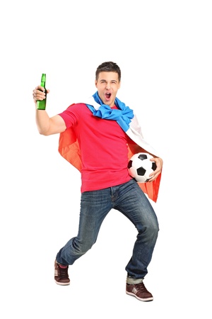 Football fan covered with dutch flag and holding a beer bottle and football cheering isolated on white backgroundの写真素材