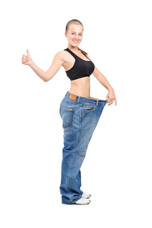 Full length portrait of a weightloss woman giving a thumb up isolated on white backgroundの写真素材