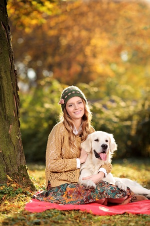 Smiling young woman hugging a labrador retreiver dog out in the parkの写真素材