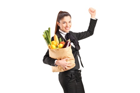 A young female holding a paper bag full of groceries isolated on white background の写真素材