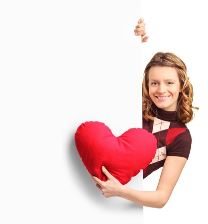  Adorable female peeking out of a banner with a red heart in her hand isolated on white backgroundの写真素材