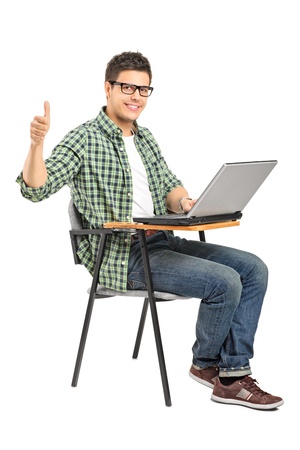 A school boy working on a laptop and giving thumb up isolated on white backgroundの写真素材