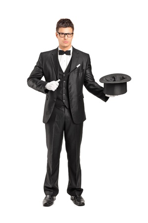 Full length portrait of a magician holding a magic wand and top hat isolated on white backgroundの写真素材