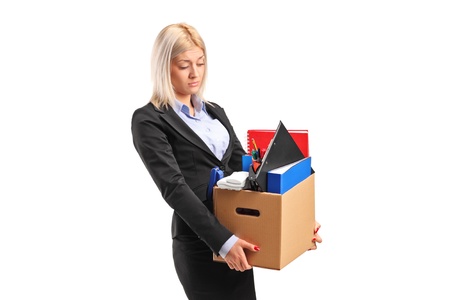 A fired businesswoman in a suit carrying a box of personal items isolated on white backgroundの写真素材