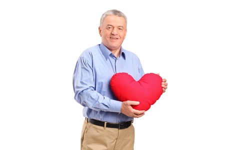A mature man holding a red heart shaped pillow isolated against white backgroundの写真素材
