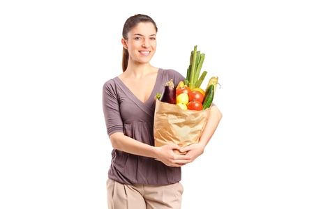 A smiling female holding a paper bag full of groceries isolated on white backgroundの写真素材