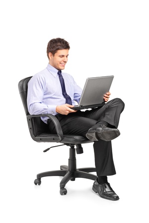 Young smiling businessman sitting in office chair and working on laptop computer isolated on white background