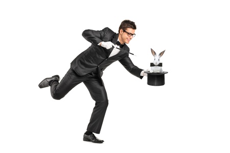 Full length portrait of a magician holding a top hat with a rabbit on it isolated on white backgroundの写真素材