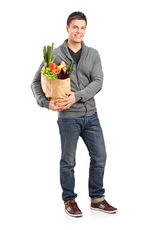 Full length portrait of a smiling male holding a paper bag full of groceries isolated on white backgroundの写真素材