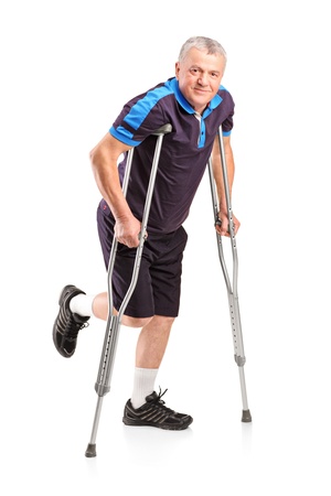 Full length portrait of an injured senior player on crutches isolated on white backgroundの写真素材