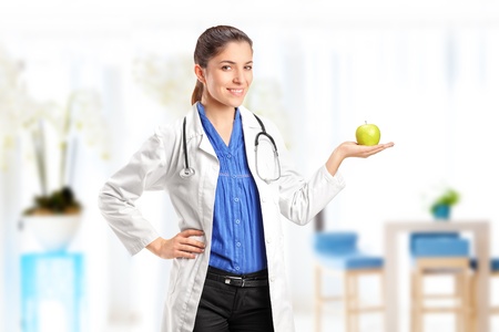 Female medical doctor or nurse with stethoscope holding an apple, in a hospitalの写真素材