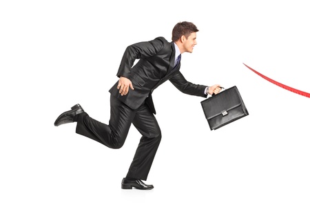 Businessman with a briefcase running towards a finish line isolated on white background の写真素材