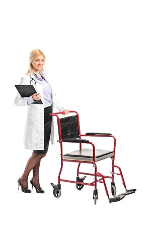 Full length portrait of a nurse holding a clipboard next to a wheelchair isolated on white backgroundの写真素材