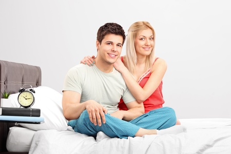 A lovely couple in pijamas sitting on a bedの写真素材