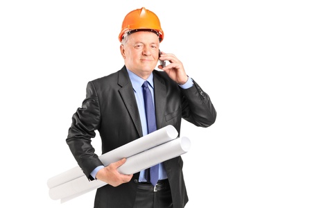 A mature construction worker holding blueprints and talking on a phone isolated on white backgroundの写真素材