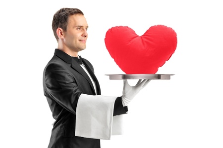 A portrait of a waiter holding a tray with a red heart shape on it isolated on white backgroundの写真素材