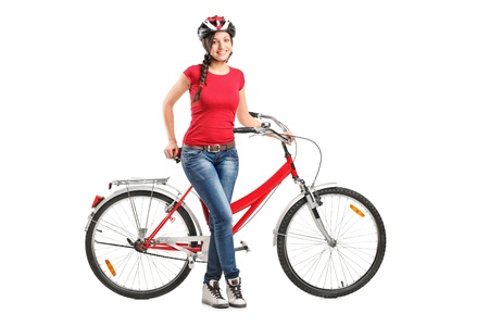 Full length portrait of a smiling female posing next to a bicycle isolated on white backgroundの写真素材