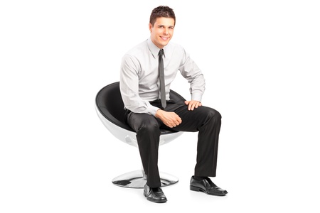 A young handsome male sitting on chair and posing isolated on white backgroundの写真素材