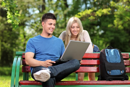 A loving couple working on a laptop in a city parkの写真素材
