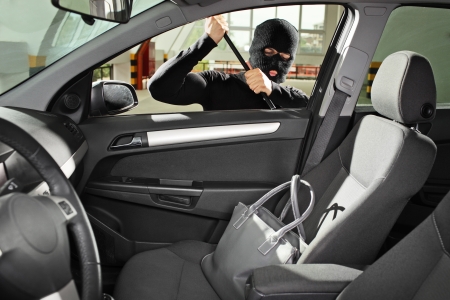A thief wearing a robbery mask trying to steal a purse bag in a automobileの写真素材