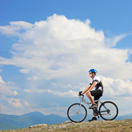 A man posing with a mountain bike on a ridge in Macedoniaの写真素材