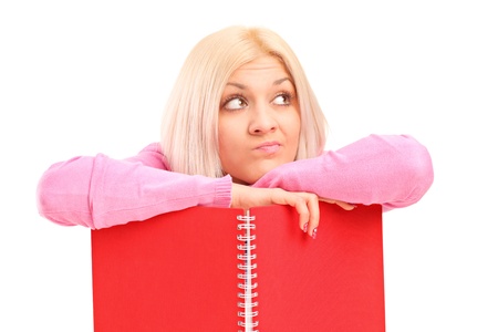 A thoughtful female holding a notebook isolated on white backgroundの写真素材
