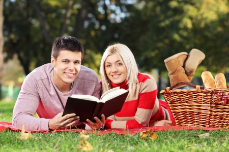 A loving couple reading a book during a picnic in city parkの写真素材