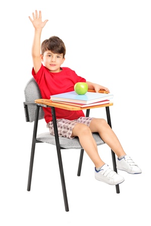 A studio shot of a schoolboy seated in a chair raising his hand isolated on white backgroundの写真素材