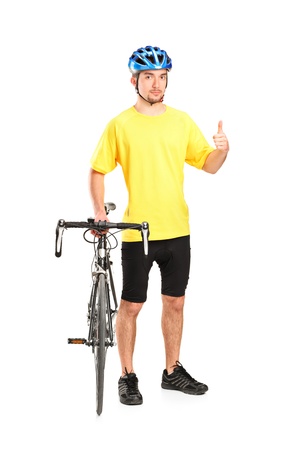 Full length portrait of a smiling bicyclist posing next to a bicycle and giving thumb up isolated on white backgroundの写真素材