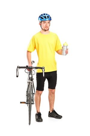 Full length portrait of a bicyclist posing next to a bicycle and holding a bottle isolated on white backgroundの写真素材