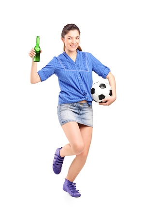 Full length portrait of a happy female fan holding a beer bottle and football isolated on white backgroundの写真素材