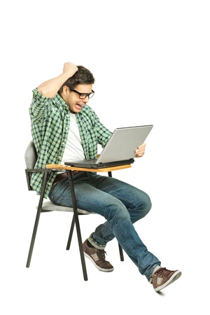 A shocked student sitting on a chair and working on a laptop isolated on white backgroundの写真素材