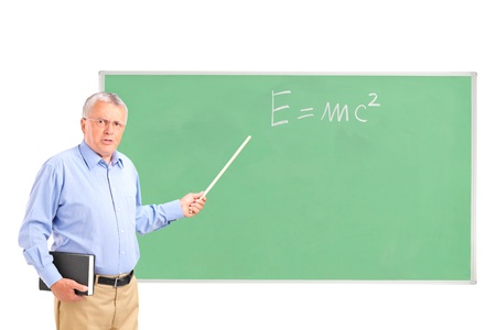 An angry mature teacher with a book in his hand and chalkboard in the backgroundの写真素材