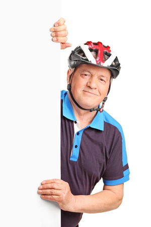 Portrait of a senior bicyclist wearing helmet and posing behind a white panel isolated on white backgroundの写真素材