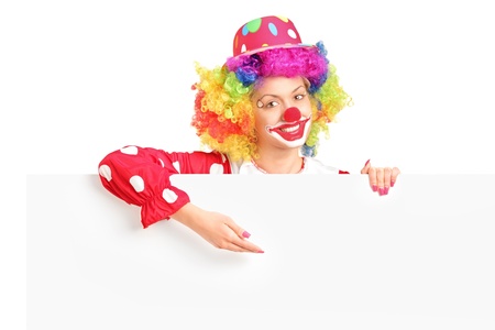 A female clown with happy joyful expression on her face posing behind a white panel isolated on white backgroundの写真素材